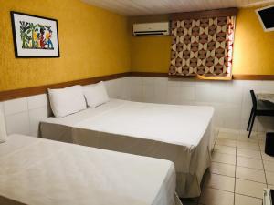 Habitación con 2 camas, mesa y ventana en Hotel Veraneio en Recife