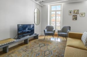 sala de estar con TV de pantalla plana y 2 sillas en MSC Flat 8, en Oporto