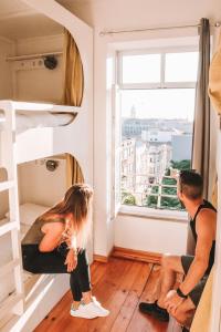 
a woman and a man sitting on a balcony looking out a window at Urban Garden Porto Central Hostel in Porto
