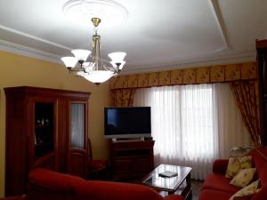 sala de estar con sofá rojo y TV en Apartamentos Los Frutales, en Arnuero