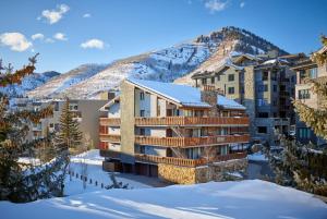 a building in the snow with a mountain in the background at Enzian - CoralTree Residence Collection in Vail