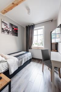 a bedroom with a bed and a desk and a window at Apartamenty Kupiecka ścisłe centrum in Zielona Góra