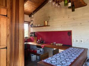 une cuisine avec une table et un mur rouge dans l'établissement Piedra y Cielo, à Punta del Diablo