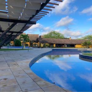 a large swimming pool with a building in the background at Winterville Resort em Gravatá/PE in Gravatá