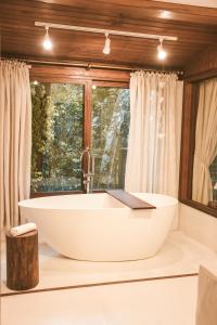 a bathroom with a large tub in front of a window at Aurora e Vale in Praia do Rosa