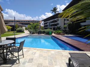 una piscina con mesa y sillas junto a un edificio en Cupe Beach Living Beira Mar - Flat 02 quartos, en Porto de Galinhas