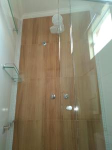 ducha con suelo de madera y puerta de cristal en Suítes da Rô - hospedaria familiar diária e temporada, en Varginha