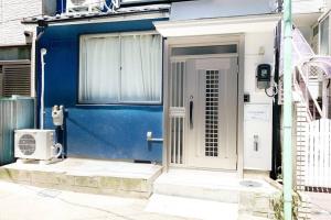 una casa azul con una puerta blanca y una puerta en Sunstay - Shinbamba 1, en Tokio