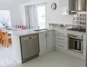 a white kitchen with a sink and a stove at The Rested Guest 3 Bedroom Cottage West Wyalong in West Wyalong