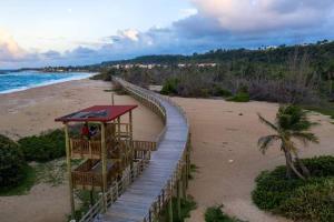 a wooden walkway on a beach with a boardwalk at Mar Bonita Beach Apartment in Isabela