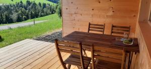 einen Holztisch und Stühle auf einer Holzterrasse in der Unterkunft Ferienwohnung Schönenbühl in Hittisau