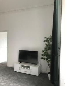 una TV a schermo piatto seduta sopra un centro di intrattenimento bianco di Carvetii - Edward House A - 2 Dbl bed 1st floor flat a Dunfermline