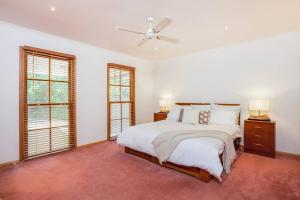 a white bedroom with a bed and two windows at Charmes, paradise by the shore in Tootgarook