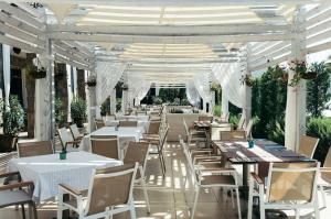 un restaurante con mesas y sillas blancas y una marquesina en Green Life Sunrise, en Sozopol