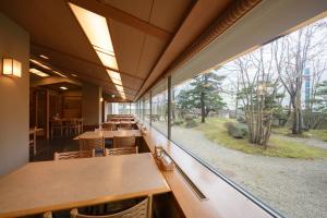 een cafetaria met tafels en een groot raam bij Grand Hotel New Oji in Tomakomai