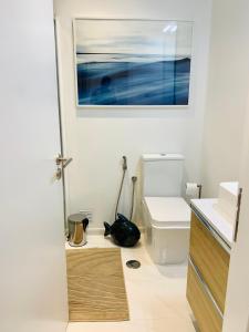 a bathroom with a black cat sitting on the floor next to a toilet at Costa Caparica surf apartment in Costa da Caparica