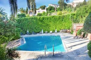 a swimming pool in a yard with a hedge at Villa lours in Le Trayas
