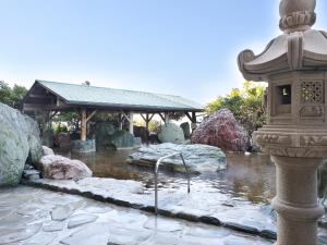 a pond in a garden with rocks and a building at Ryugujo Spa Hotel Mikazuki Ryugutei in Kisarazu