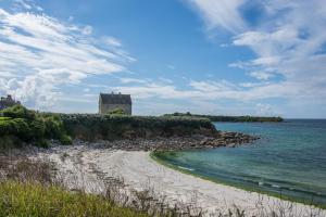 una spiaggia con un edificio in lontananza e l'oceano di La Chambre d'Alexandre a Santec
