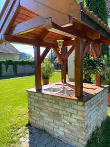an outdoor kitchen with a wooden pergola on a brick wall at Kocsis Apartman és Camping in Mosonmagyaróvár