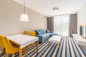 uma sala de estar com uma mesa e cadeiras e um sofá em Perfect Holiday Apartments Bel Mare by Renters em Międzyzdroje