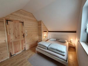 a bedroom with a bed and a wooden wall at Domki w Nowicy in Nowica