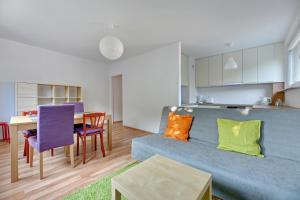 a living room and kitchen with a blue couch and a table at Wave Apartments - Tysiąclecia in Gdańsk