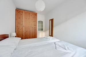 a bedroom with a large white bed and a wooden cabinet at Wave Apartments - Tysiąclecia in Gdańsk