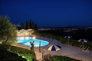 a large swimming pool with umbrellas at night at Alfresco luxury Villa with Heated pool in Montecatini Terme