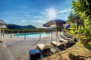 a swimming pool with lounge chairs and an umbrella at Alfresco luxury Villa with Heated pool in Montecatini Terme