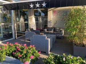 a patio with chairs and flowers in front of a store at Hôtel Gardenia Bordeaux Est in Yvrac