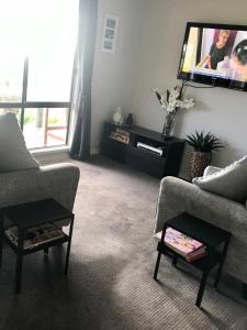 a living room with two chairs and a flat screen tv at Pine View Holiday Rental in Emu Bay