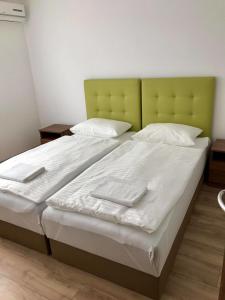 a large bed with white sheets and a green headboard at Veritas Apartment Zamárdi in Zamárdi