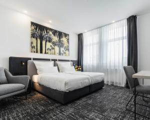 a bedroom with a bed and two chairs and a window at Libarty Hotels in Weinstadt