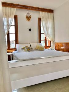 a bedroom with a large white bed with windows at Kekova Hotel in Kaş