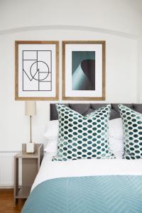 1 dormitorio con 1 cama con almohadas azules y 2 fotografías en FW Haute Apartments at North Finchley, a 3 Bedroom and 2 Bathroom Pet-Friendly Flat, King or Twin beds with FREE WIFI, en Finchley