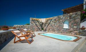 a patio with a pool and two chairs and a table at Petra Residence Mini Pool Spa in Adamas