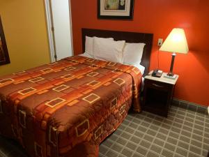 a hotel room with a large bed and a lamp at Scottish Inns Wrightstown in Wrightstown