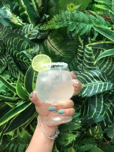 une femme tenant un verre de limonade devant les plantes dans l'établissement La Vita Mũi Né, à Phan Thiết