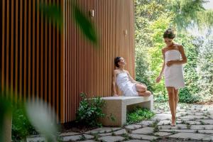a woman in a white dress standing next to a woman sitting on a bench at Hotel Apollo Terme in Montegrotto Terme