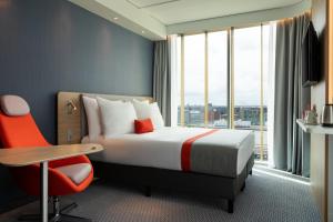 a hotel room with a bed and a desk and a window at Holiday Inn Express Amsterdam - North Riverside by IHG in Amsterdam