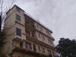 a tall building with a balcony with people on it at Prem Home Stay in Sundarnagar
