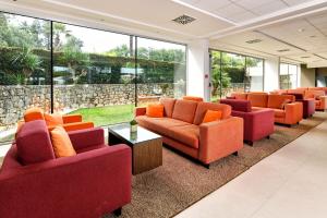 a waiting room with orange couches and a wall of windows at Hotel Mediteran Plava Laguna in Poreč
