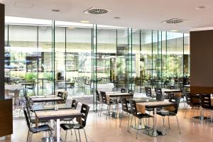 a restaurant with tables and chairs and glass walls at Hotel Mediteran Plava Laguna in Poreč