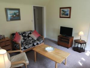a living room with a couch and a tv at Annslea Garden Cottage in Pitlochry