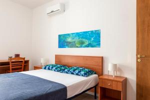 una camera da letto con un letto con cuscini blu e un dipinto di CATONA HOUSE a Otranto