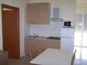 uma cozinha com um frigorífico branco e uma mesa com cadeiras em Residence MILANO em Chieuti