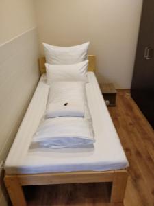 uma pequena cama com lençóis brancos e almofadas em Dorottya Vendégház em Hódmezővásárhely