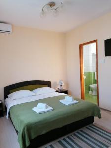 a bedroom with a large bed with two towels on it at Apartmani Sara Trebinje in Trebinje