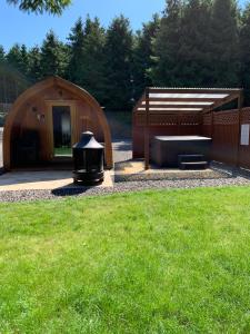 ein großes Holzgebäude mit einem Grill im Hof in der Unterkunft Kersebrock Kabins in Falkirk